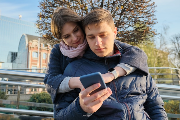 Jovem casal lendo o texto no telefone, fundo de cidade de primavera