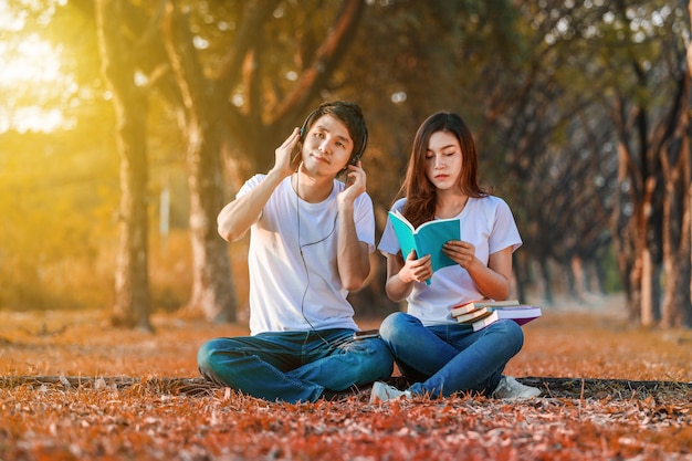 jovem casal lendo um livro e ouvir música com fone de ouvido no parque