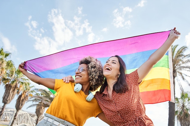 Foto jovem casal lésbico celebra dia do orgulho com bandeira arco-íris conceito de homossexualidade gay