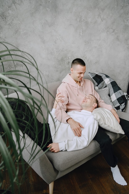 Jovem casal lgbtq romântico, passando o dia acariciando e relaxando no sofá. conceito de estilo de vida familiar diferente.