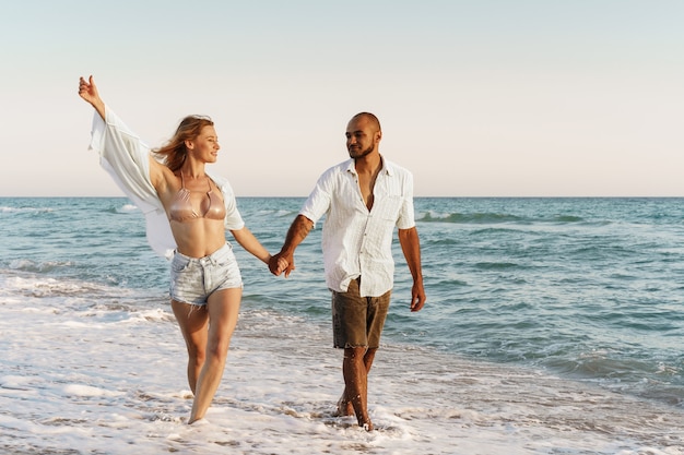 Jovem casal lindo caminhando na praia perto do mar