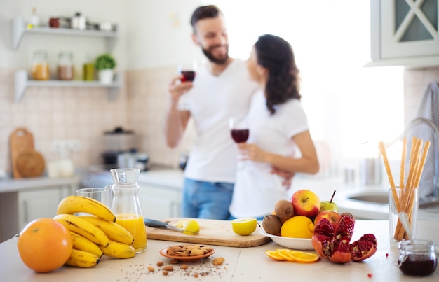 Jovem casal lindo e animado, apaixonado, cozinhando na cozinha e se divertindo juntos enquanto fazem salada de frutas frescas