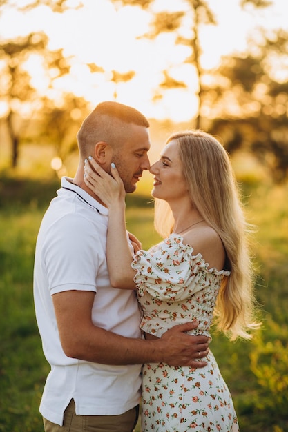 Jovem casal lindo em branco dançando no fundo do pôr do sol