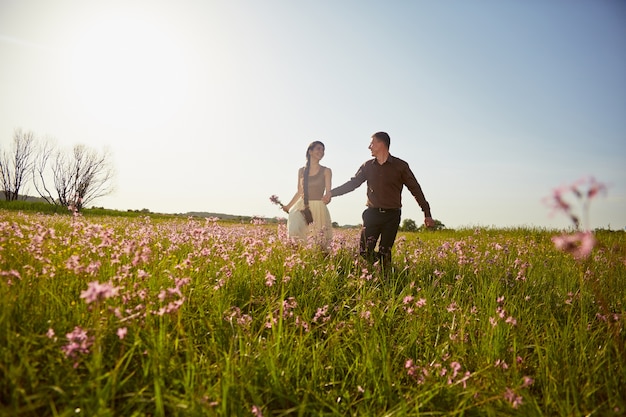 Jovem casal lindo em um campo com flores