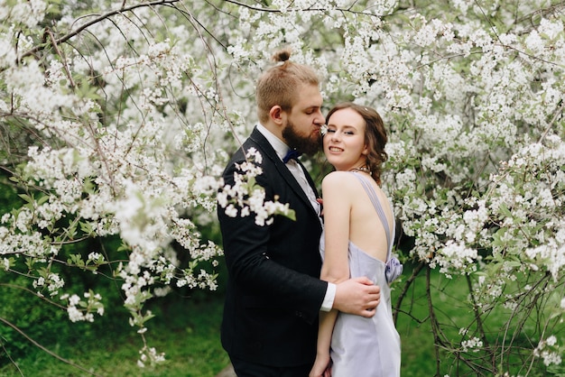 Jovem casal lindo no jardim no contexto de flores de cerejeira 1