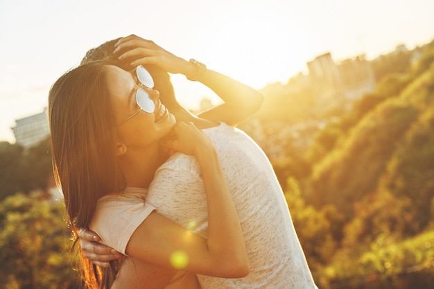 Jovem casal lindo se abraçando e sorrindo enquanto passa o tempo ao ar livre