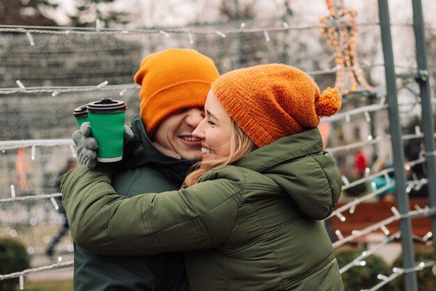 Jovem casal lindo se divertindo ao ar livre segurando café e se sentindo aquecido e feliz