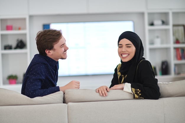 Jovem casal muçulmano aproveitando o tempo juntos em casa durante o Ramadã. Feliz família árabe assistindo TV