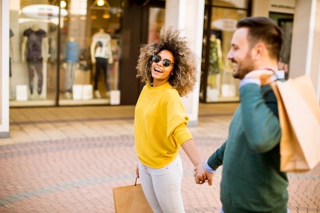 Jovem casal multiétnico com sacos no shopping