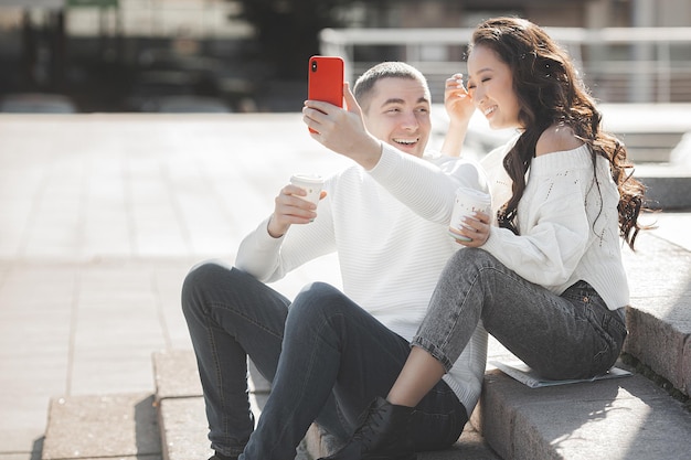 Jovem casal multirracial fazendo foto de selfie no celular. Homem e mulher se divertindo juntos. Jovens falando em um smartphone.