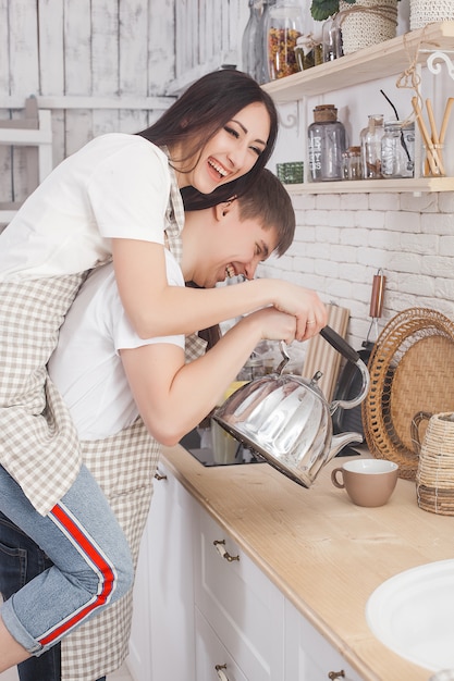 Jovem casal na cozinha. Homem e mulher cozinhando. Namorado e namorada dentro de casa na cozinha.