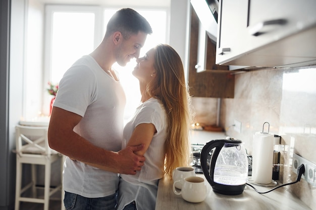 Jovem casal na manhã juntos em pé na cozinha moderna.