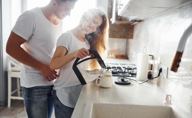 Jovem casal na manhã juntos em pé na cozinha moderna.