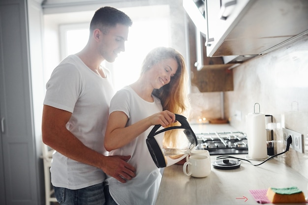 Jovem casal na manhã juntos em pé na cozinha moderna.