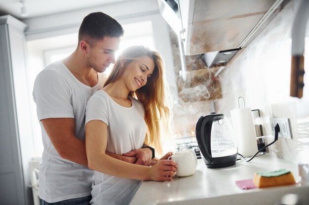 Jovem casal na manhã juntos em pé na cozinha moderna.