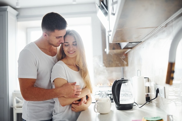 Jovem casal na manhã juntos em pé na cozinha moderna.