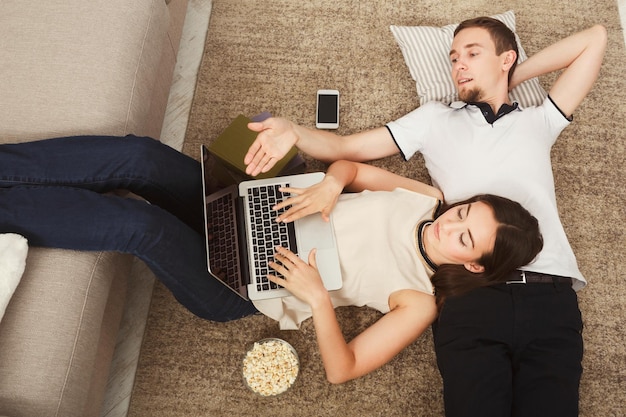 Jovem casal navegando na web em um laptop, sentado no sofá em casa, relaxando, copie o espaço, vista de cima