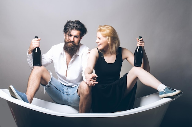 Jovem casal no banho com garrafas de vinho