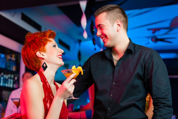 Jovem casal no bar ou clube bebendo cocktails