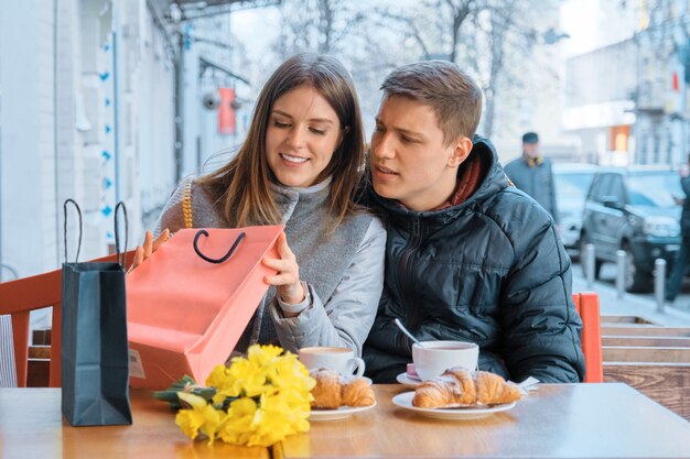 Jovem casal no café ao ar livre com sacos de compras