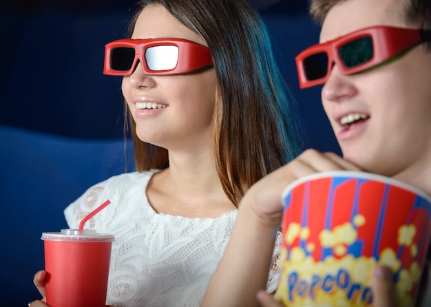 Jovem casal no cinema assistindo a um filme com pipoca.