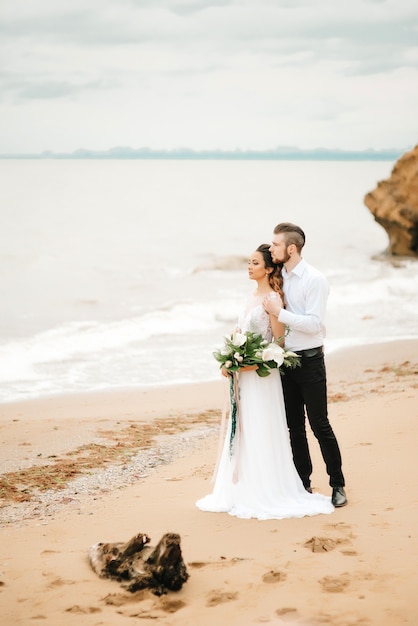 Foto jovem casal noivo com a noiva em uma praia em uma caminhada de casamento