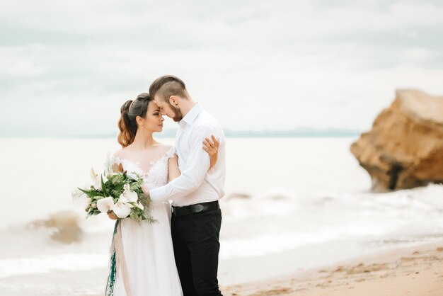 Jovem casal noivo com a noiva em uma praia em uma caminhada de casamento