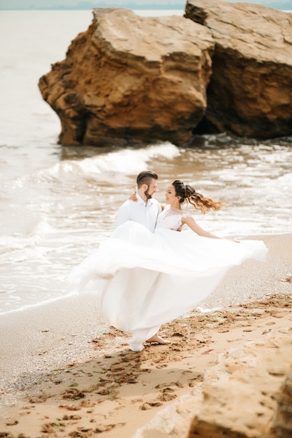 Foto jovem casal noivo com a noiva em uma praia em uma caminhada de casamento