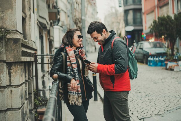 Jovem casal olhando um celular falando e rindo sobre isso