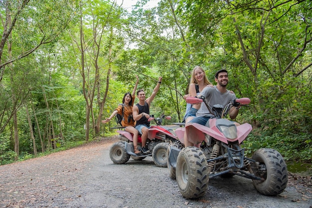 jovem casal ou amigo feliz enquanto andava de quadriciclo na floresta