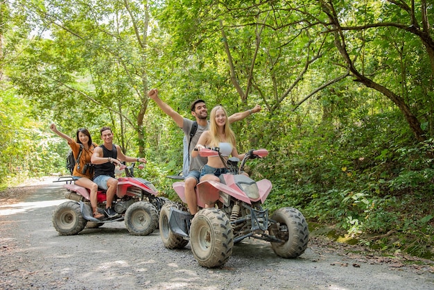 Jovem casal ou amigo feliz enquanto andava de quadriciclo na floresta