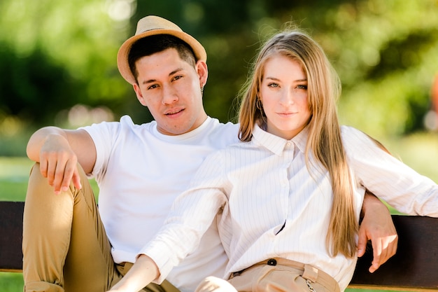 Jovem casal posando e assistindo a câmera. Homem latino e mulher branca olhando para a câmera felizes e sorrindo