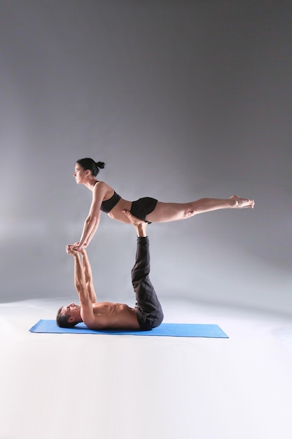 Jovem casal praticando acro yoga no tapete em estúdio juntos Acroyoga Couple yoga Parceiro yoga