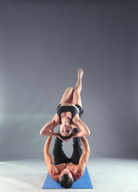 Jovem casal praticando acro yoga no tapete em estúdio juntos Acroyoga Couple yoga Parceiro yoga