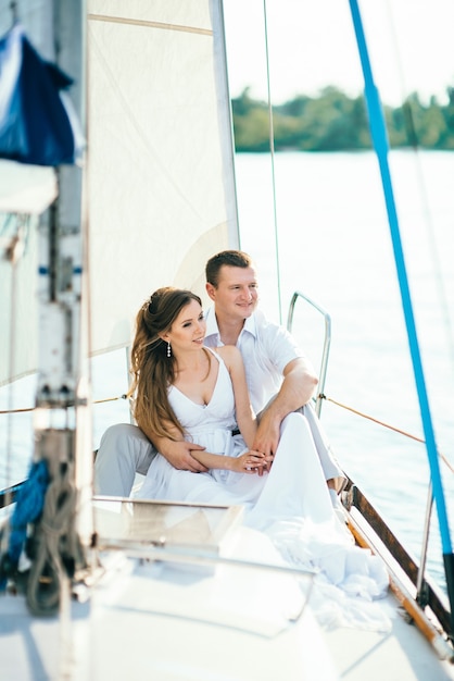 Jovem casal rapaz e rapariga num iate à vela branco