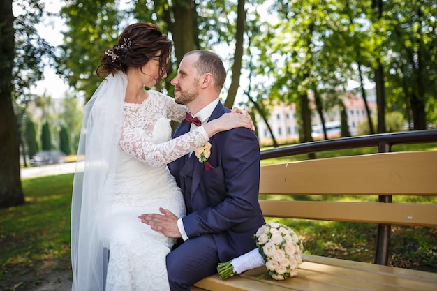 Jovem casal recém-casados beijando em um banco de parque