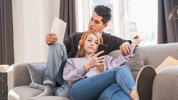 Jovem casal relaxando e passando algum tempo juntos no sofá enquanto está em casa.