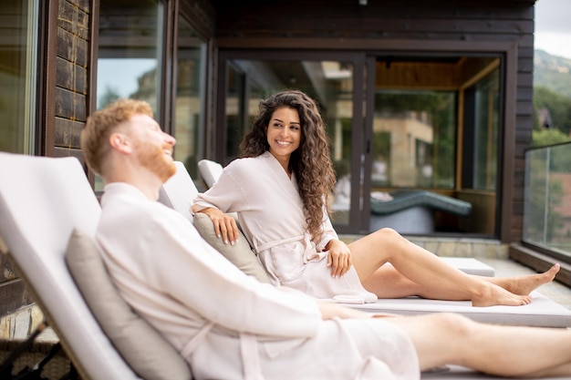 Jovem casal relaxando em camas no terraço ao ar livre