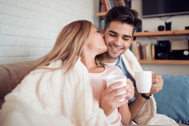 Jovem casal relaxando em um sofá e bebendo café