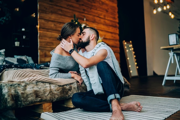 Jovem casal romântico beijando no quarto em luzes de Natal