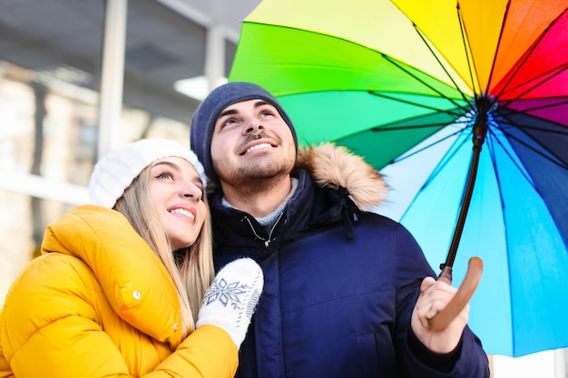 Jovem casal romântico com guarda-chuva colorido na rua da cidade