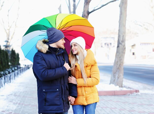 Jovem casal romântico com guarda-chuva colorido na rua da cidade