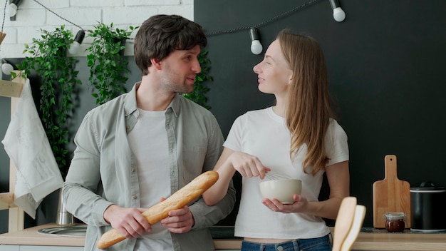 Jovem casal romântico cozinhando na cozinha e se divertindo muito