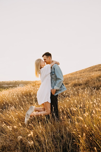 Jovem casal romântico em um campo, abraçando e sorrindo.