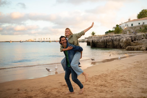Jovem casal romântico se divertindo enquanto caminhava na praia ao pôr do sol