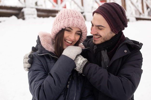 Jovem casal se abraçando no parque no inverno.