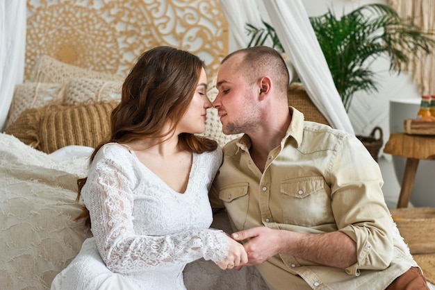 Jovem casal se beijando ao lado da cama.