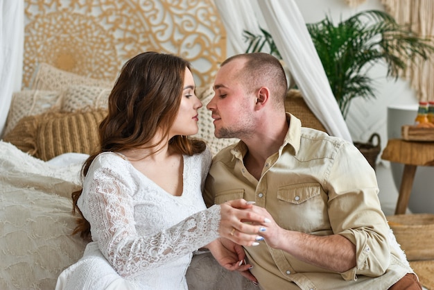 Jovem casal se beijando ao lado da cama.