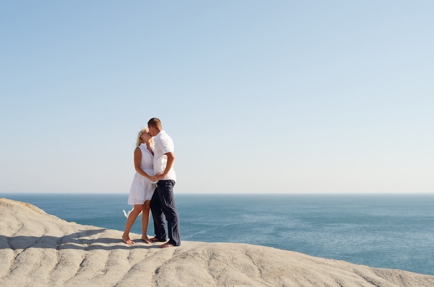 Jovem casal se beijando em um penhasco perto do mar
