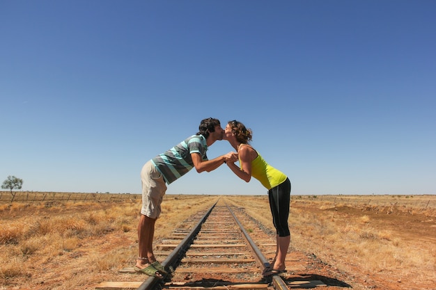 Foto jovem casal se beijando na ferrovia no deserto no outback austrália. conceito de amantes de mochileiros